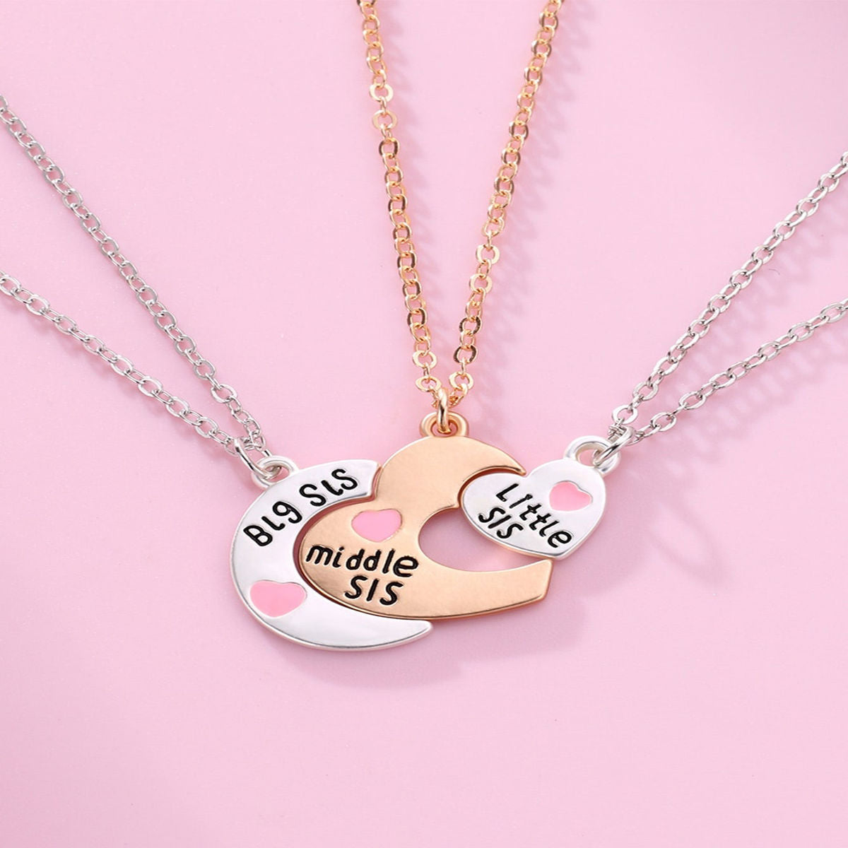 A 3-piece sister necklace set featuring interlocking heart-shaped pendants labeled "Big Sis," "Middle Sis," and "Little Sis" with silver and gold chains.
