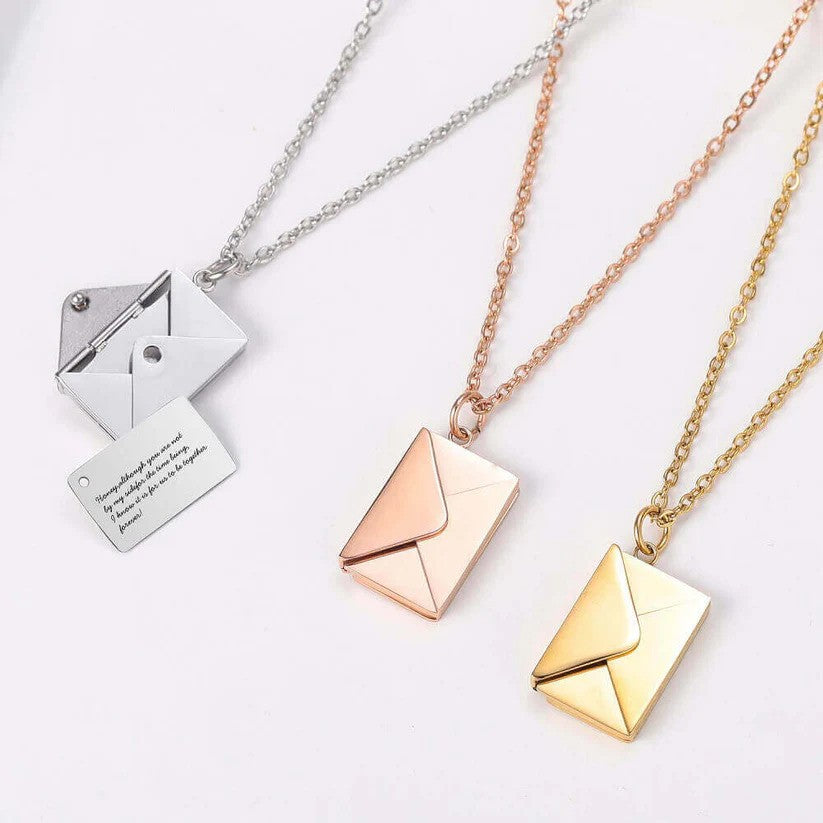 Three Custom Engraved Love Letter Necklaces in gold, rose gold, and silver. The silver necklace is open, revealing an engraved message inside.