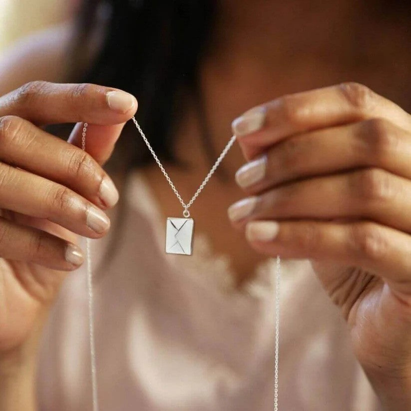 A person holding a silver Custom Engraved Love Letter Necklace.